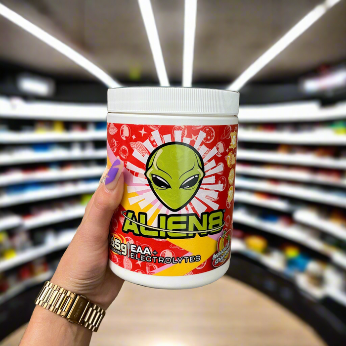 Close-up of (Alien8 EAA + Electrolytes 465g) held up inside My Supplement Shop, clearly showing the front label in a Sports Nutrition setting.