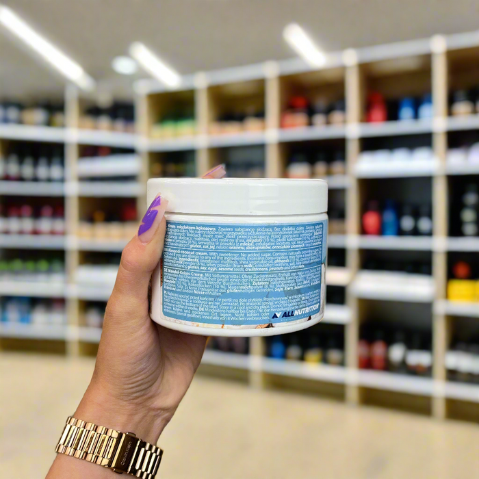 Close-up of (Allnutrition Nutlove Coco Crunch 500g) held up inside My Supplement Shop, clearly showing key ingredients on the packaging in a Sports Nutrition setting.