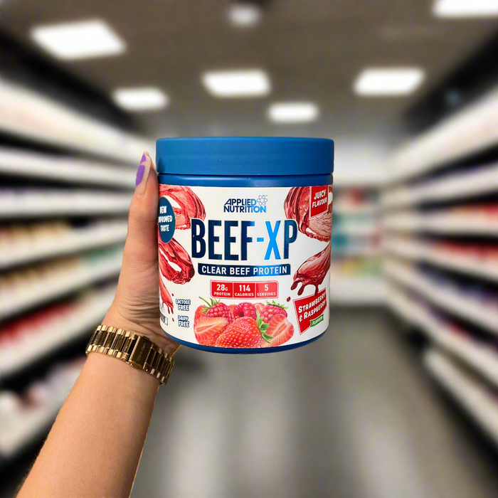 Close-up of (Applied Nutrition Beef-XP 150g) held up inside My Supplement Shop, clearly showing the front label in a Sports Nutrition setting.
