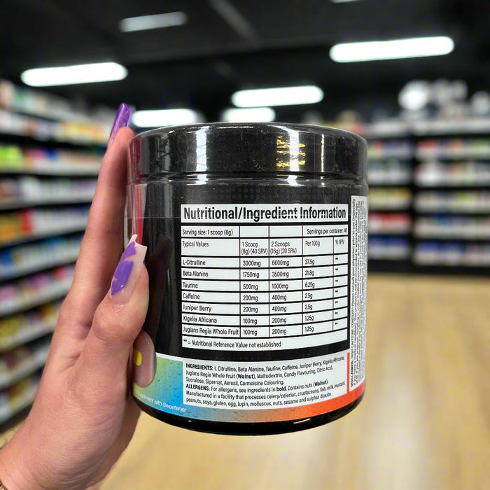 Close-up of (Trained By JP DNFM New Pre Workout 320g) held up inside My Supplement Shop, clearly showing Nutritional Values on the packaging in a Sports Nutrition setting.